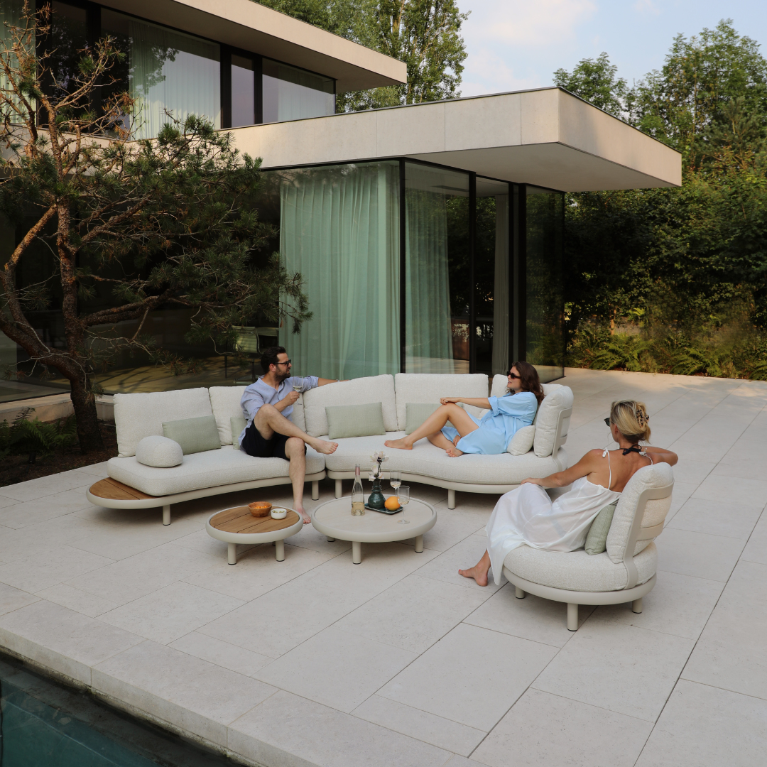 Modern luxury outdoor seating area with curved sofas and armchairs on a poolside patio, perfect for relaxed social gatherings.