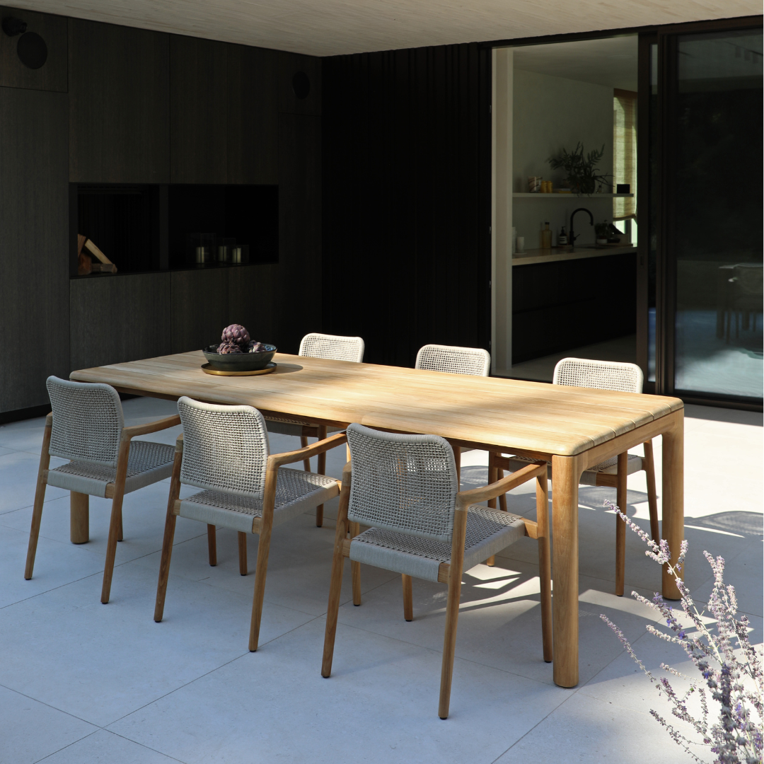 Teak outdoor dining table with woven chairs on a modern outdoor terrace
