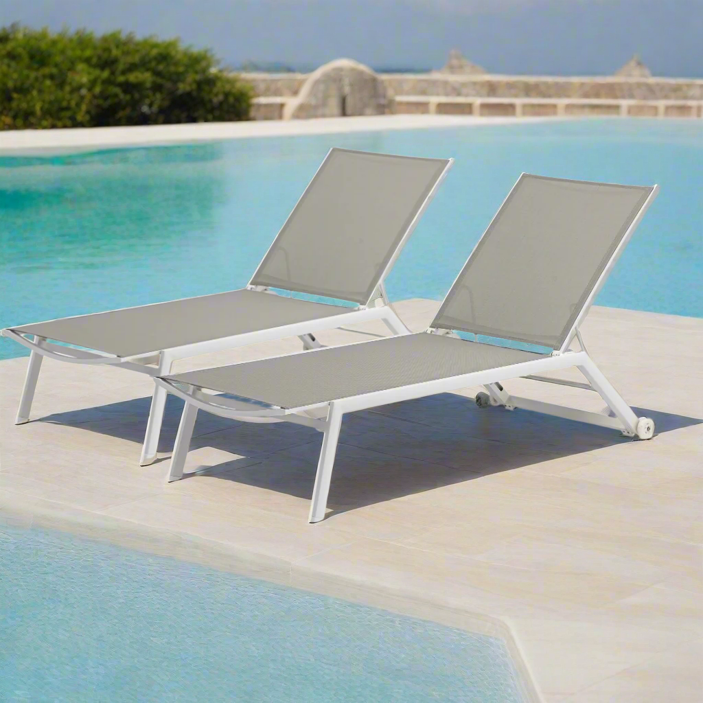 Pair of sleek white outdoor loungers arranged beside a luxury pool area with a clean contemporary aesthetic.