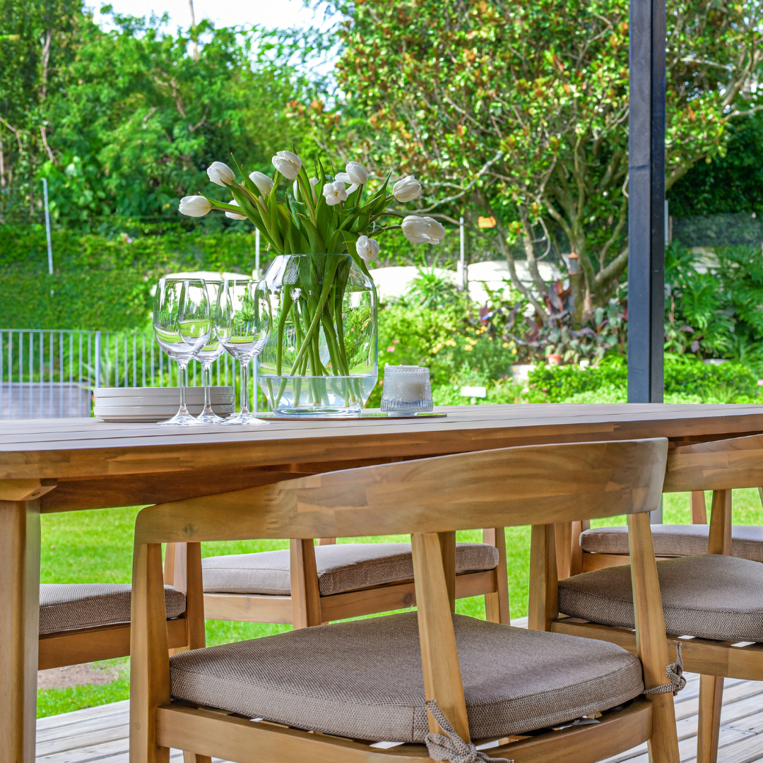 Wooden outdoor dining chairs with cushions under table
