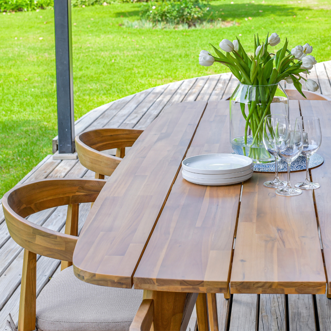 Solid wood outdoor dining table with curved edges on patio