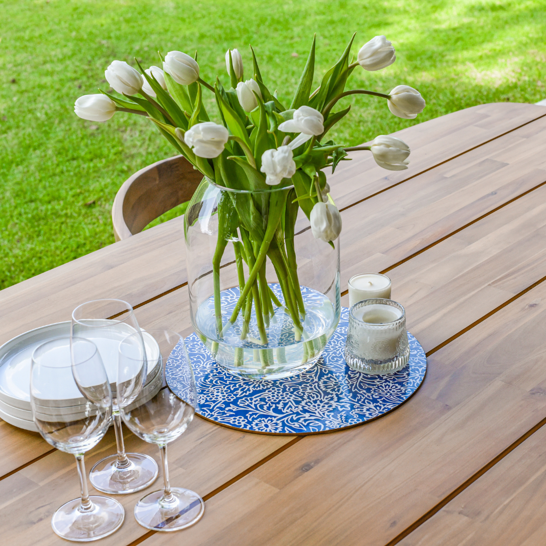 Wooden outdoor dining table styled with vase and glassware